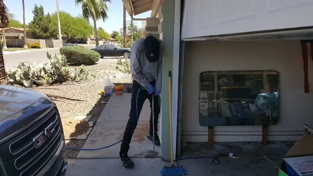 Person drilling holes for termite control in a garage
